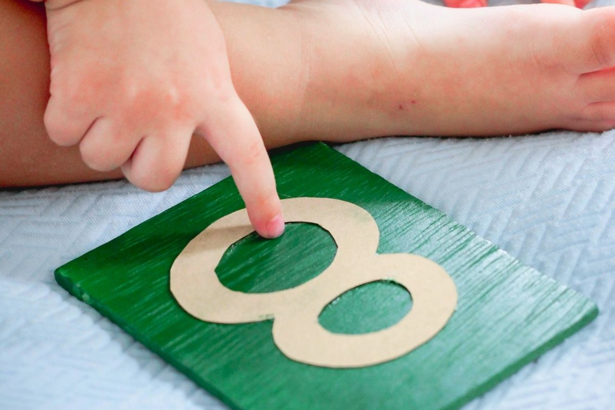 Little fingers explore the textured surface of a Montessori Sandpaper Number