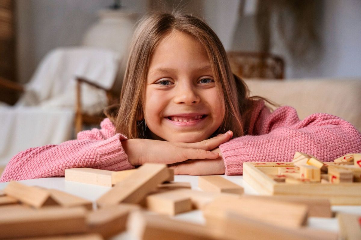 A smiling young girl works independently on a learning activity in a Montessori classroom. She has freedom to explore while following the guidelines for the activity.