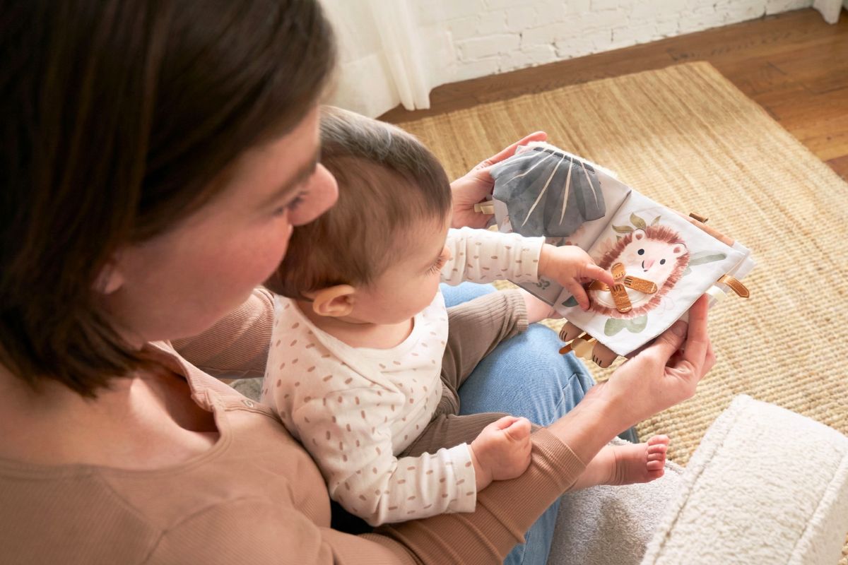 Parent and 6-month-old baby exploring a soft fabric book together
