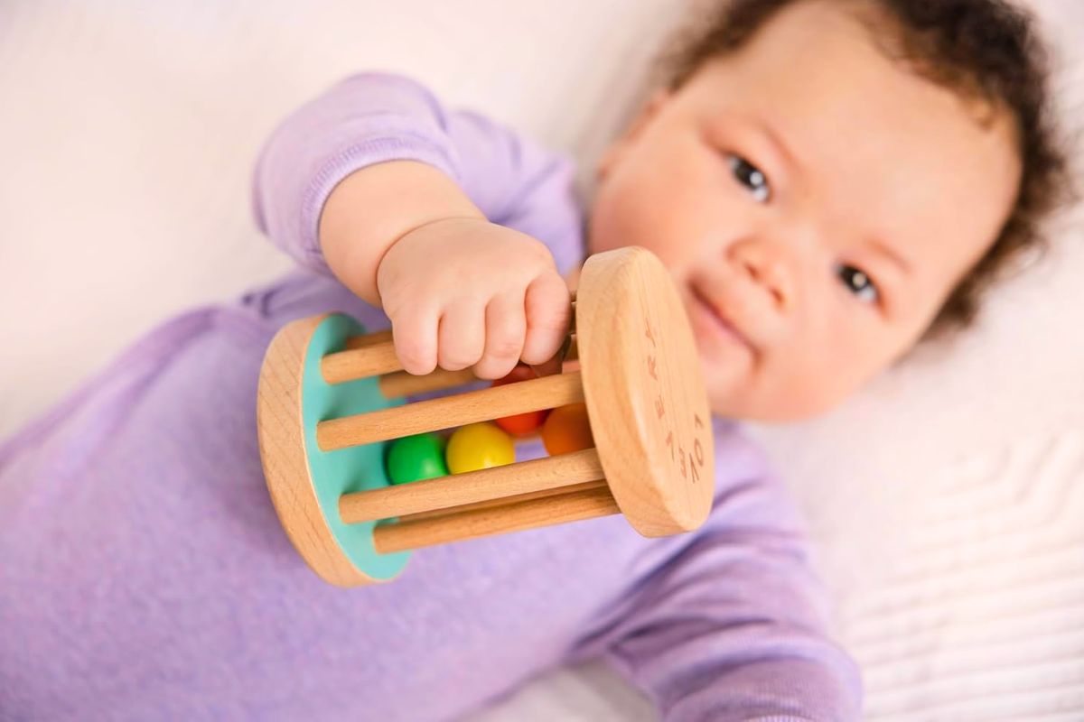 6-month-old baby exploring a lovevery wooden bell rattler