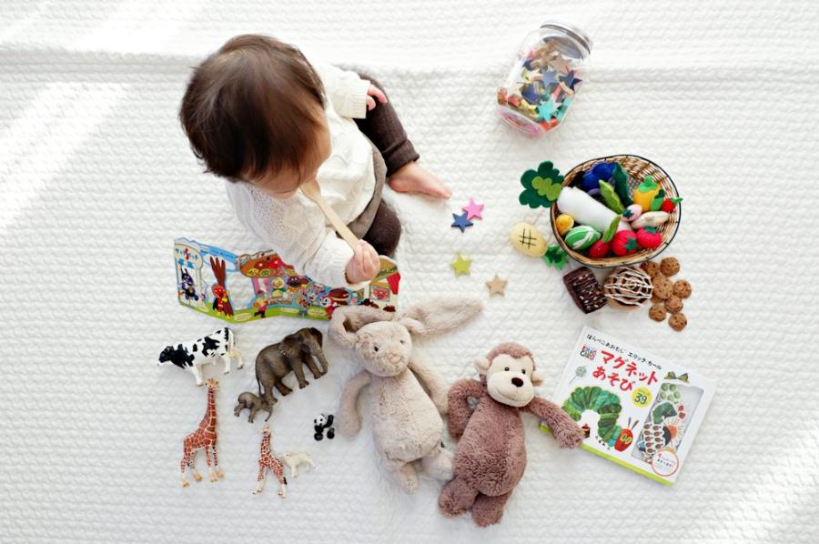 Toddler sitting on a blanket surrounded by many toys