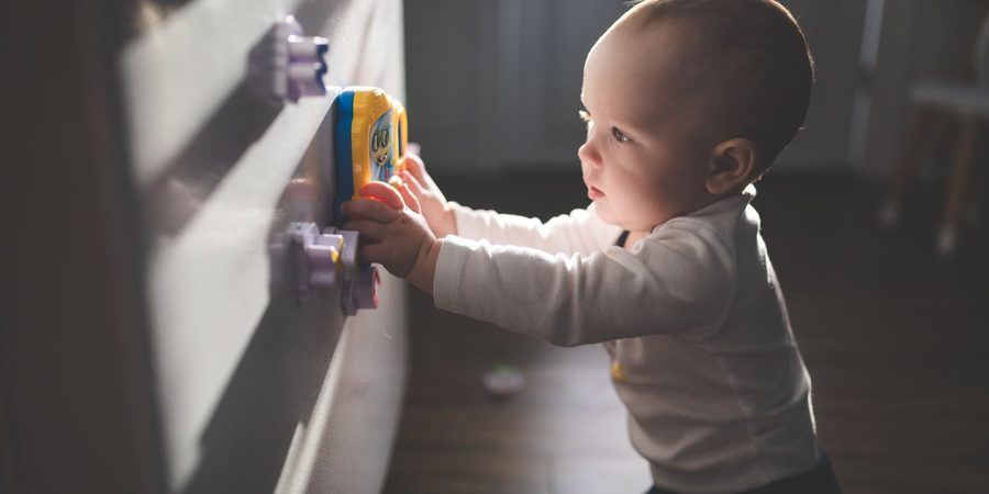 Baby standing at a wall toy panel