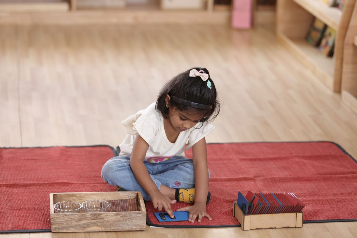 Girl working with wooden trays on a rug