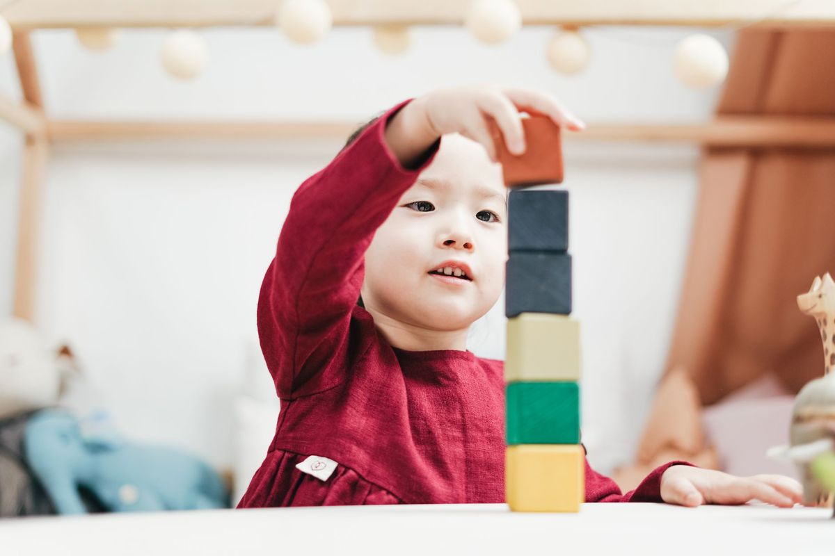 Young child stacking colorful wooden blocks into a tower