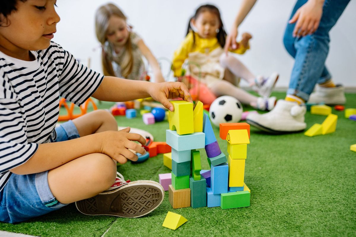 Children building a tall tower with colorful blocks on a rug