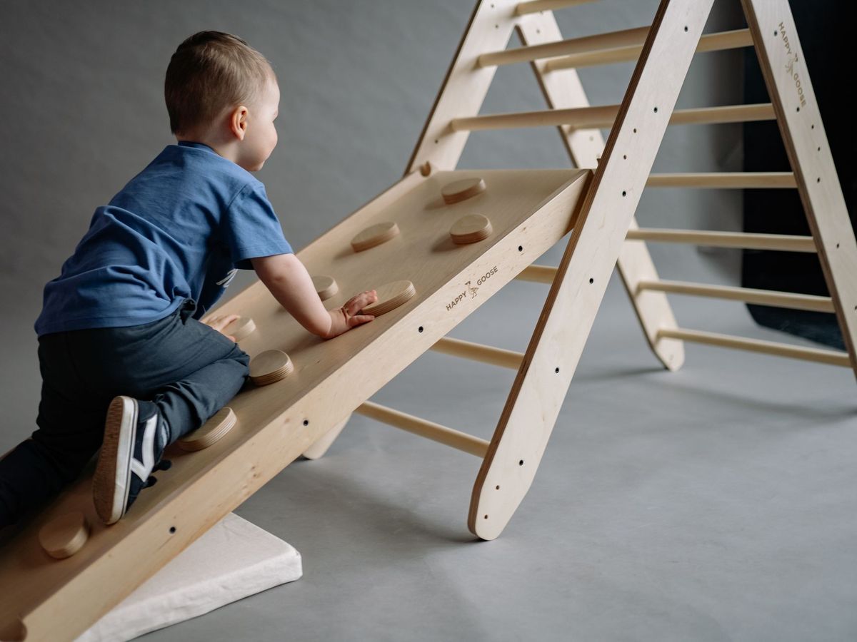 Boy climbing a wooden climbing triangle