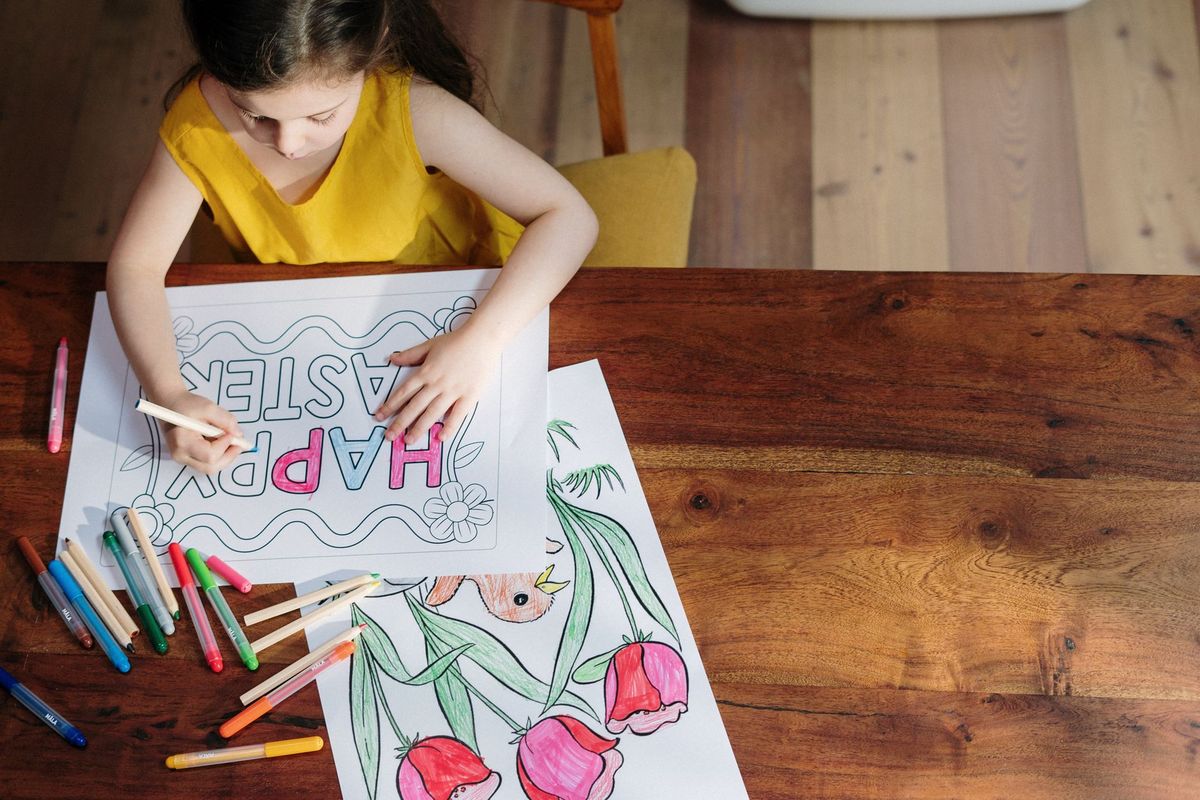 Girl coloring a large drawing with colored pencils