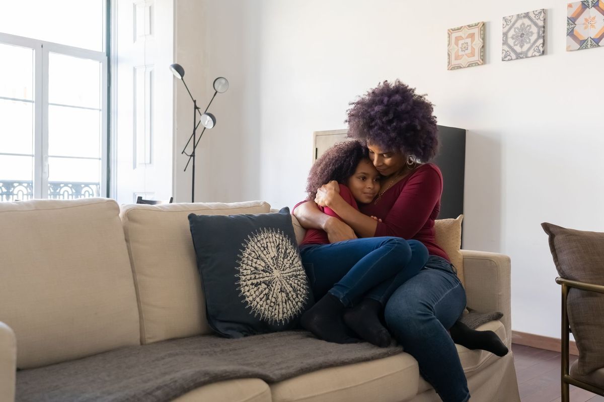 Mother hugging her daughter on the sofa after a hard moment